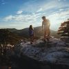 Couple hiking on Hanging Rock Trail in Hanging Rock State Park with mountains in distance and sun in distance