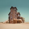 Large beach house standing alone surrounded by sand during daytime