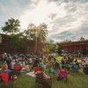 Crowd of people sitting on lawn in front of stage at First Friday Festival in Southern Pines during daytime