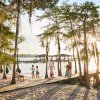 Large family walking in from dock onto beach with pier and sun in background